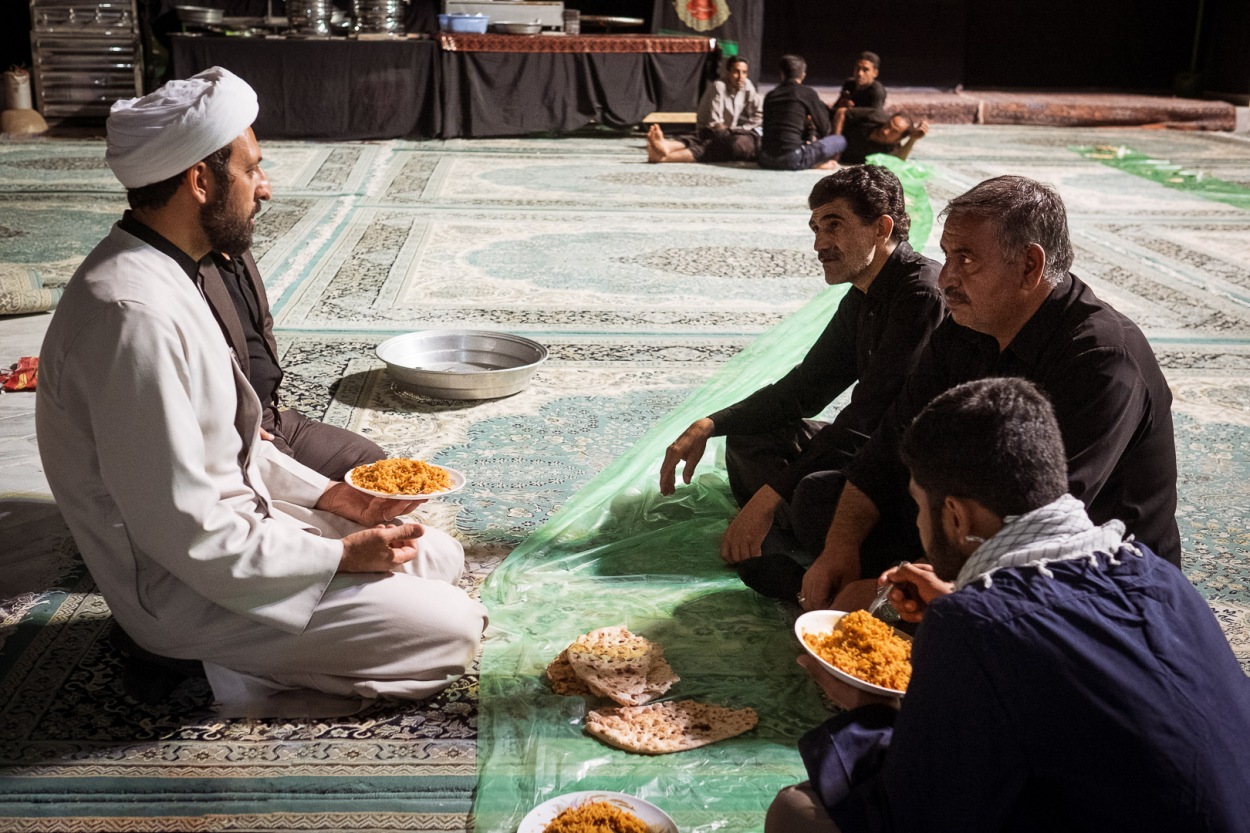 Sheikh Ali Mir Jalili sharing some rice with members of a husseinieh in Ashkezar, Yazd province (Iran).  Thousands of meals, called nazri,  are prepared by members of different husseiniehs. Nazri is later distributed among the people to remember the siege that Imam Hussein and his followers and relatives suffered during the Battle of Kerbala. Nobody remains hungry or thirsty in the town. Even if you do not seek food or drinks, you will get some on your way.